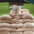 A stack of large beige burlap sacks filled with Peru washed arabica coffee beans, with a single sack standing upright on top showing the brand name Copan Trade.